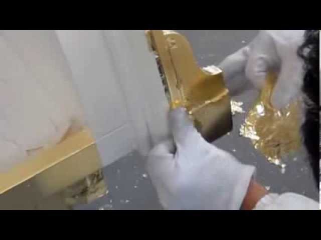 Craftsman hand-applying gold leaf to Italian cabinet