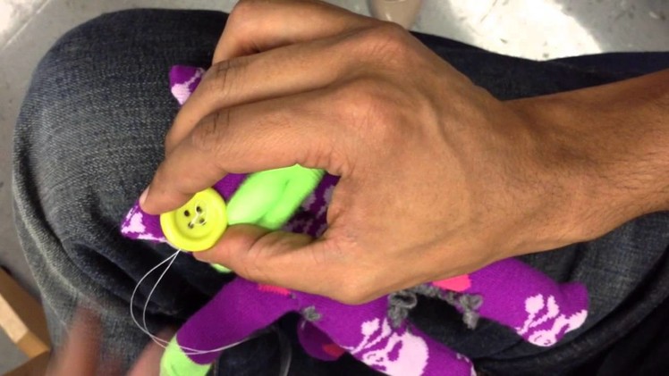 Sewing a button unto the sock creature