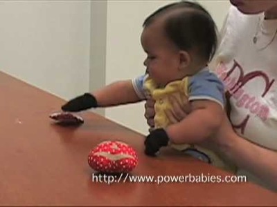 Baby picking up objects using Grabby Gloves from powerbabies.com