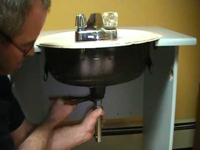 Old plumber shows how to install a drain on a bathroom sink (basin).Mechanical P.O.plug