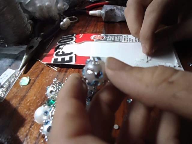 Gluing Swarovski crystals with E6000 glue onto vintage button pendants to make a pair of earrings